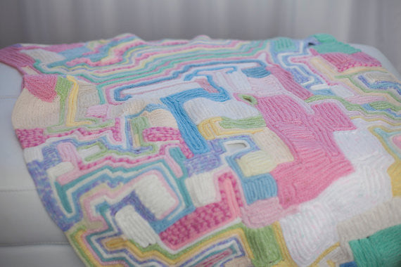 baby cot blanket made of recycled wool scraps. All pastel colors. Looks like the land from above. French knitted art